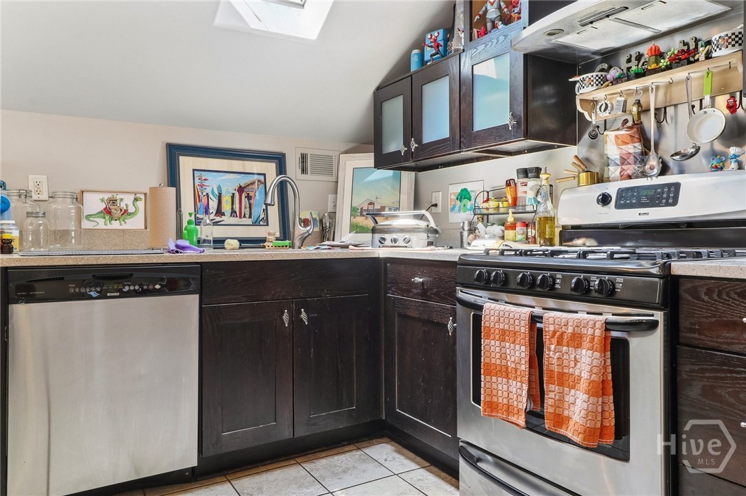 Kitchen with dark wood cabinets, stainless steel appliances, and colorful collectibles on the counters and walls.