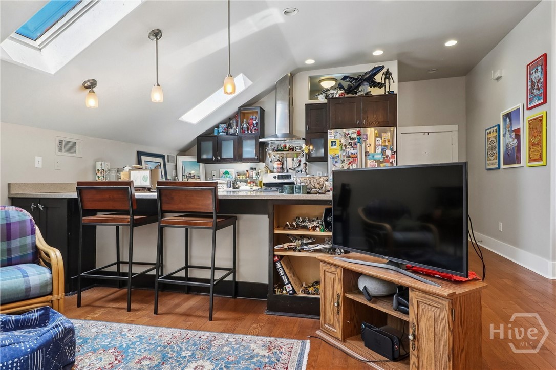 Open kitchen and living area with a breakfast bar, skylights, and a large television.