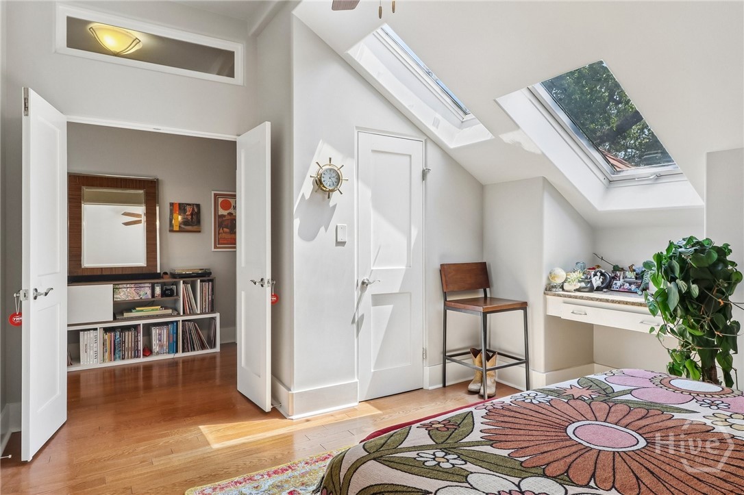 Attic bedroom with skylights, a floral bedspread, and an open doorway to a bookcase.
