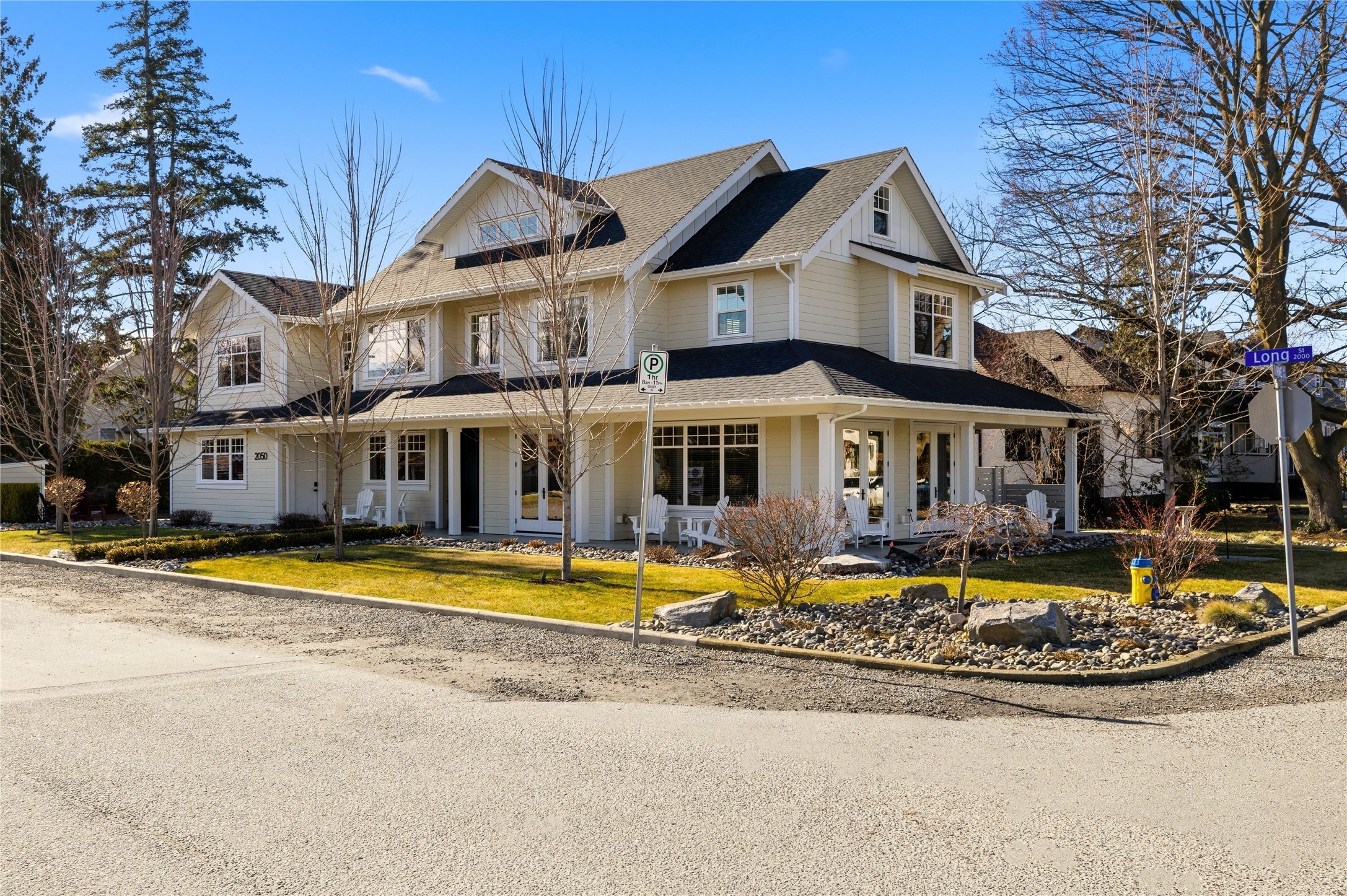 Cream two-story house with multiple gables, a covered porch, and a landscaped front yard.
