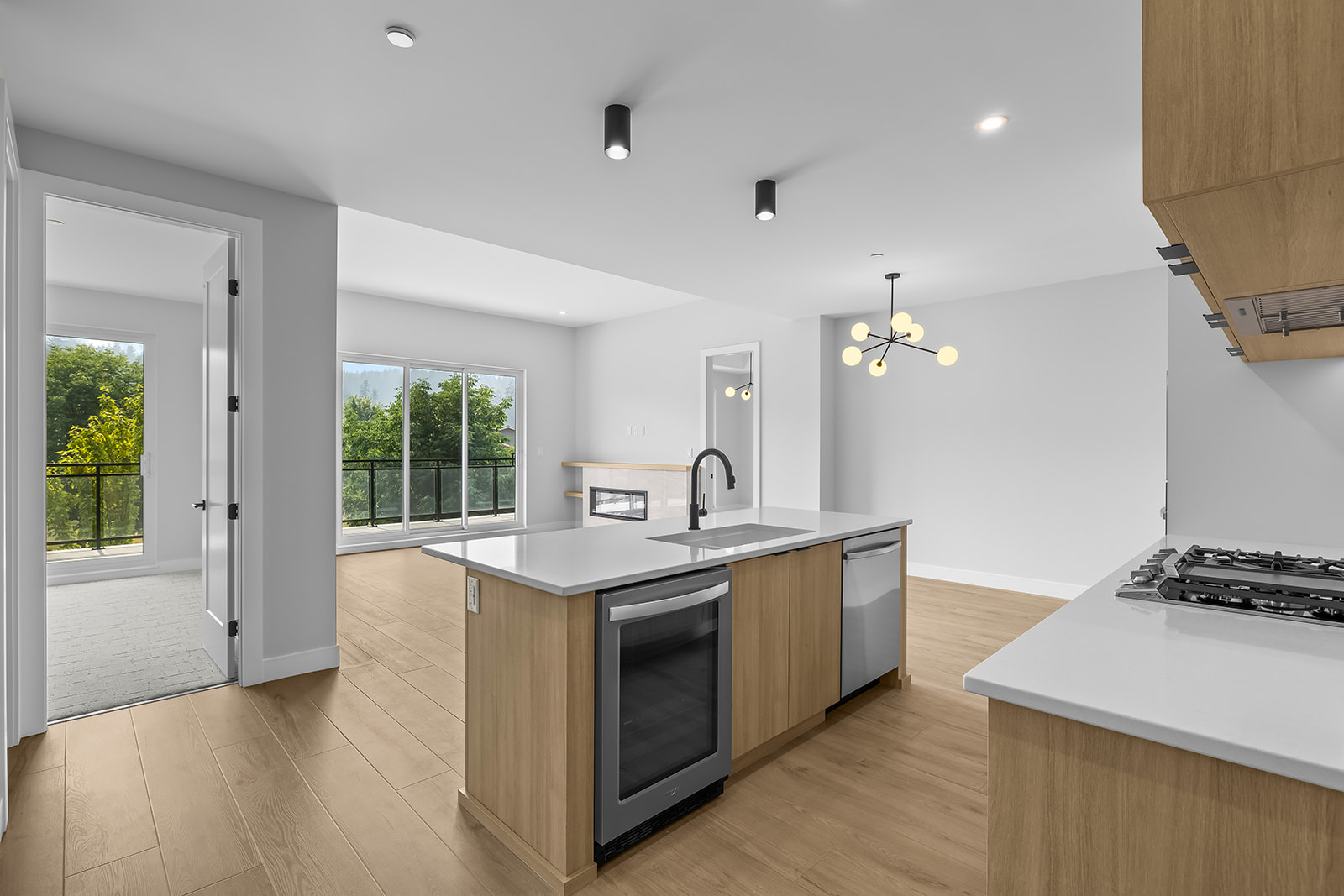 Modern kitchen with a wood-fronted island, built-in wine fridge, and sliding doors to a leafy balcony.