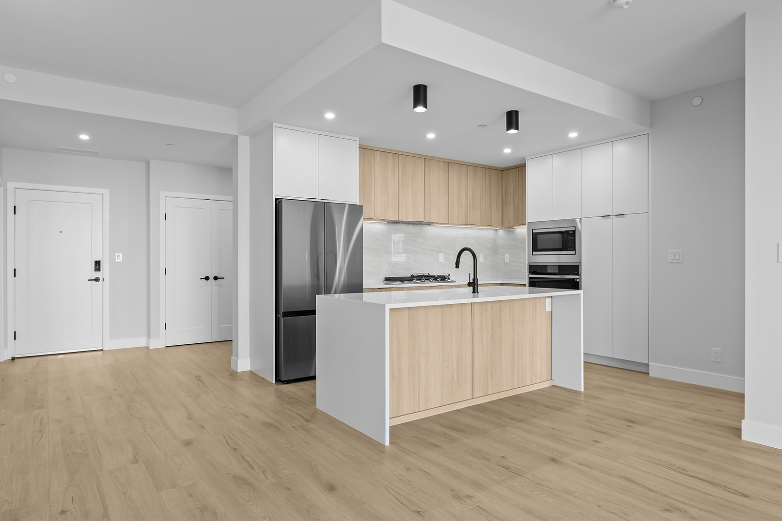 Modern kitchen with light wood cabinetry, stainless steel appliances, and a large island.