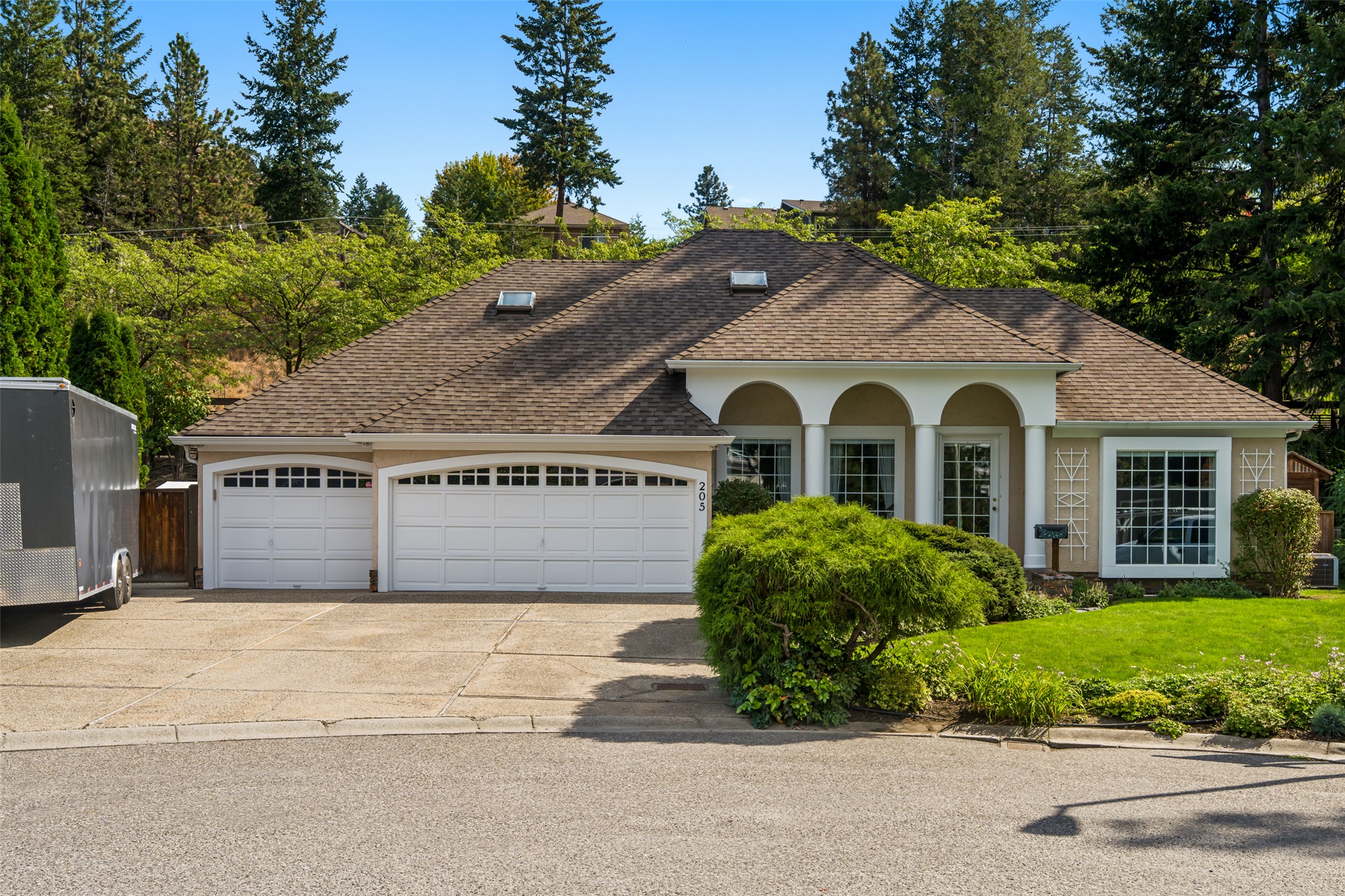 Single-story house with a two-car garage, arched entry, and landscaped front yard.