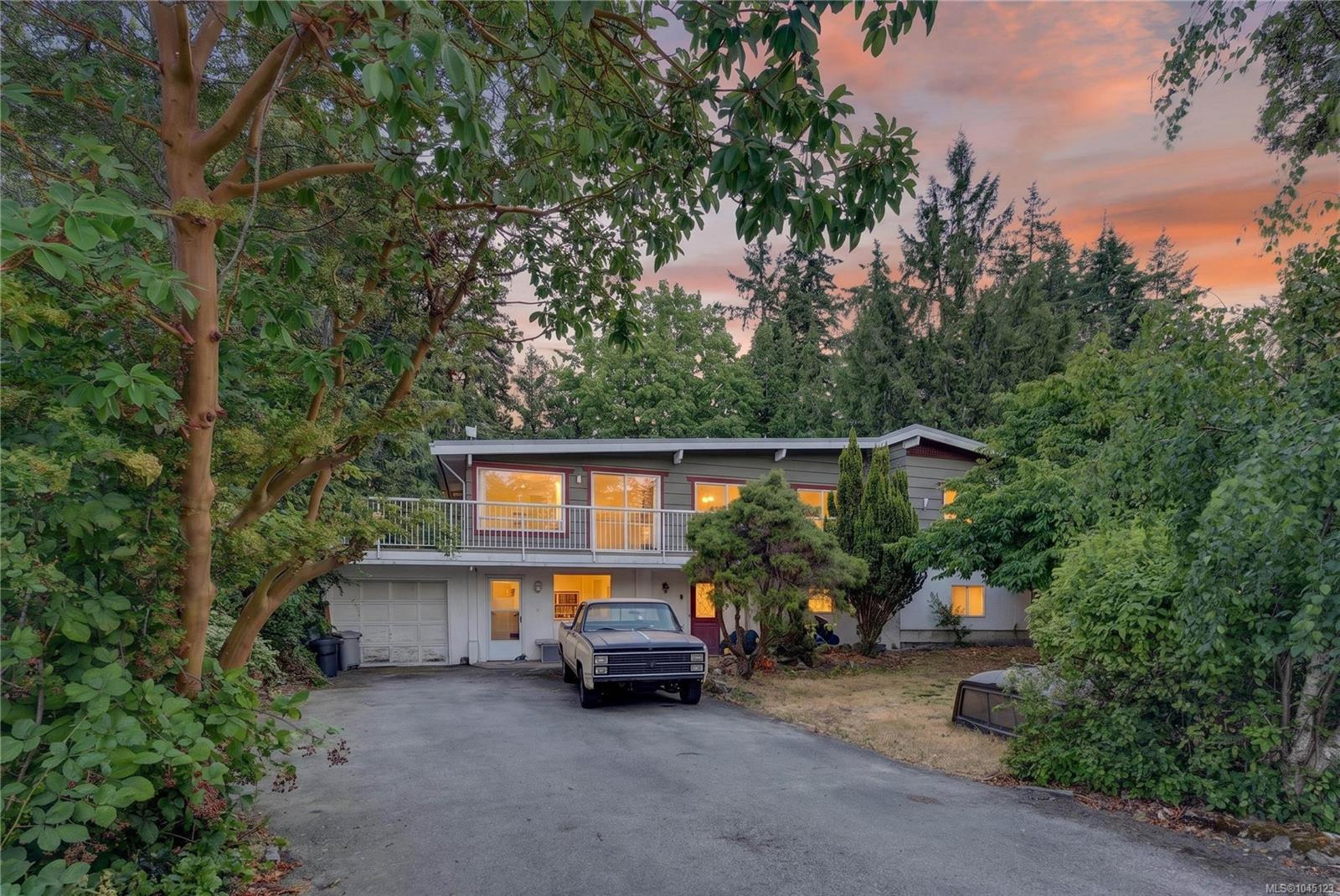 Two-story house with a balcony and vintage pickup truck in the driveway at dusk.