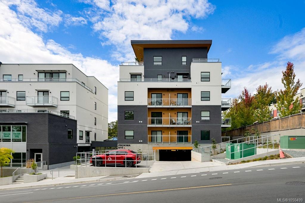 Modern apartment building with glass balconies and a red car at the entrance.
