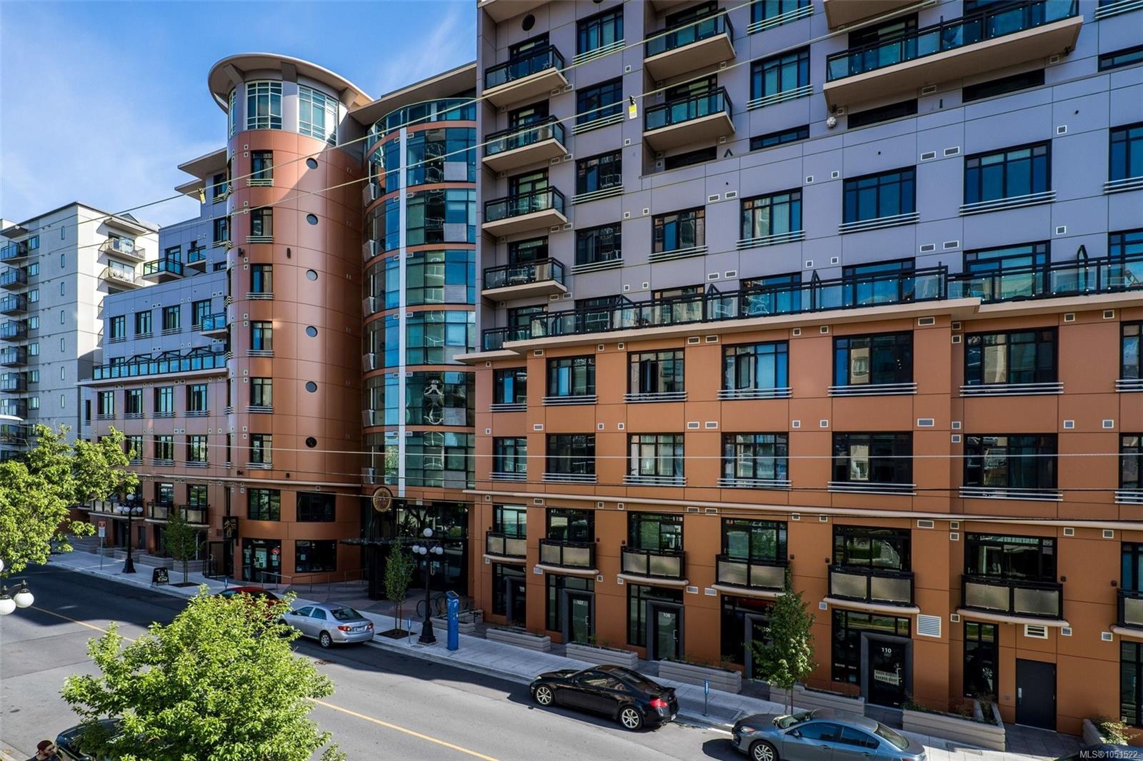 Modern condominium building with glass balconies and curved orange and lavender facade sections.