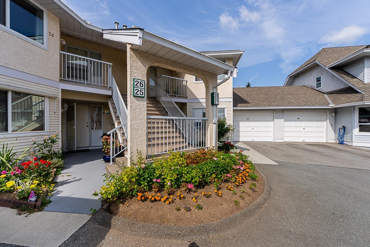Multi-unit building with shared stairways, attached garages, and flower beds.