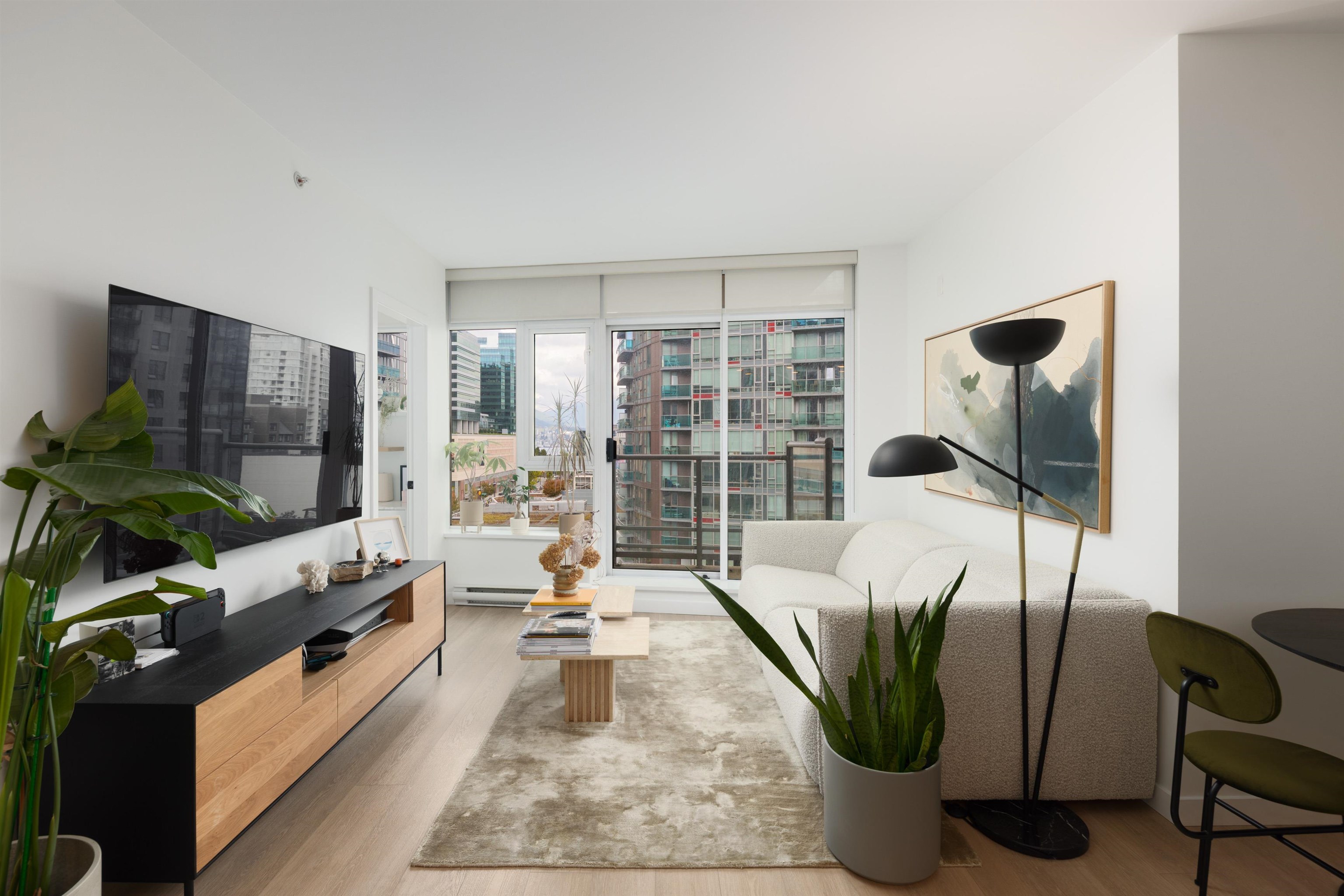 Contemporary condo living room with a white sofa and large windows overlooking city buildings.