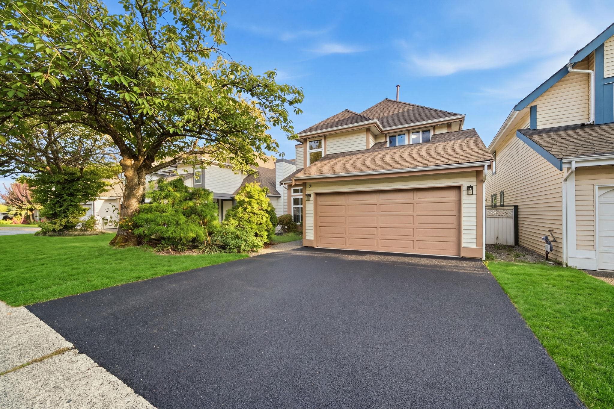 Two-story house with a double garage, broad driveway, and mature landscaping.