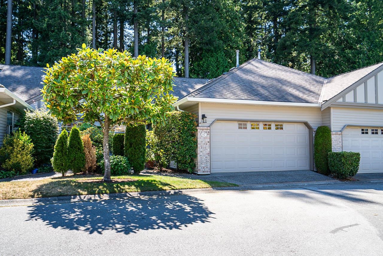 Attached home with a double garage and landscaped garden beneath mature trees.