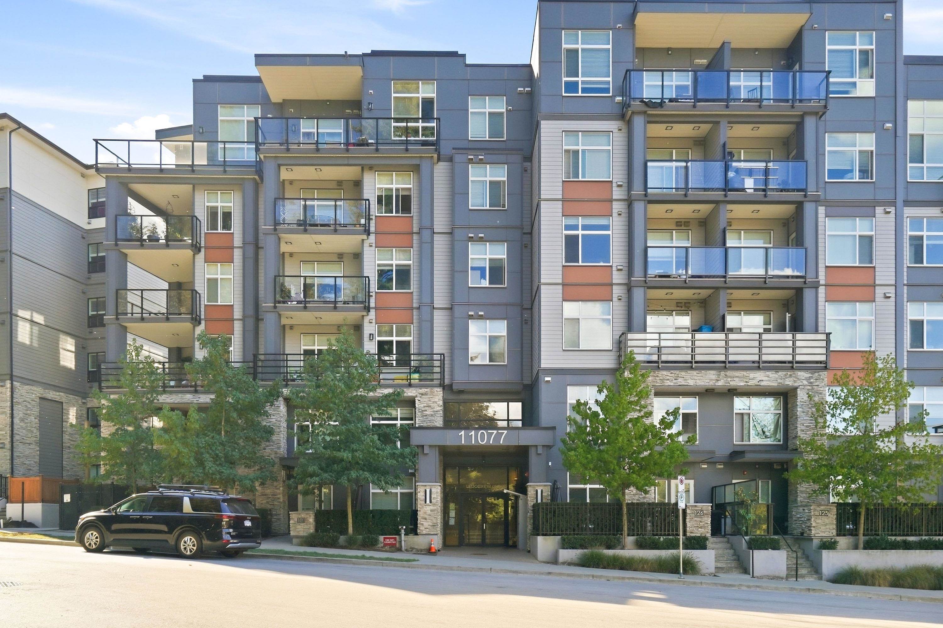 Condominium building with glass-railed balconies, stone accents, and 11077 above the entrance.