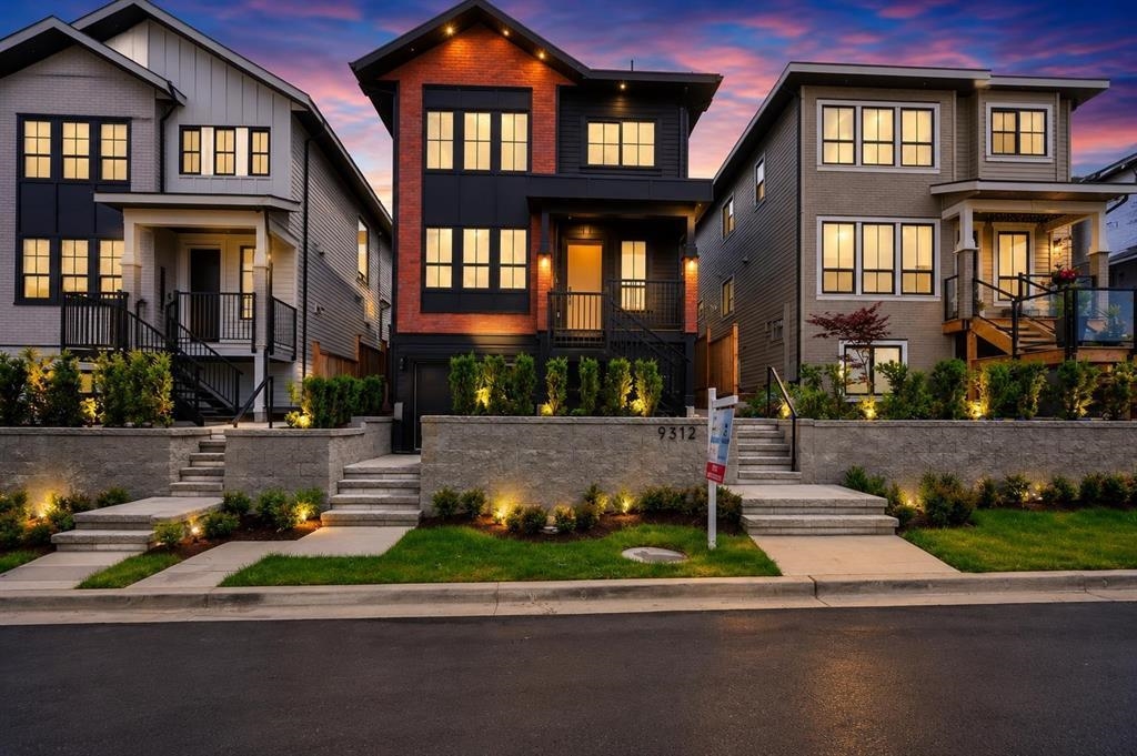 Three modern homes at dusk, with glowing windows, landscaped yards, and stone retaining walls.