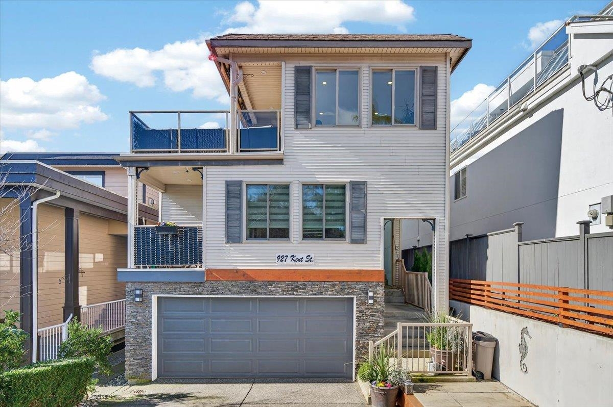 Two-story house with a stone-front garage, wide gray door, and two balconies.