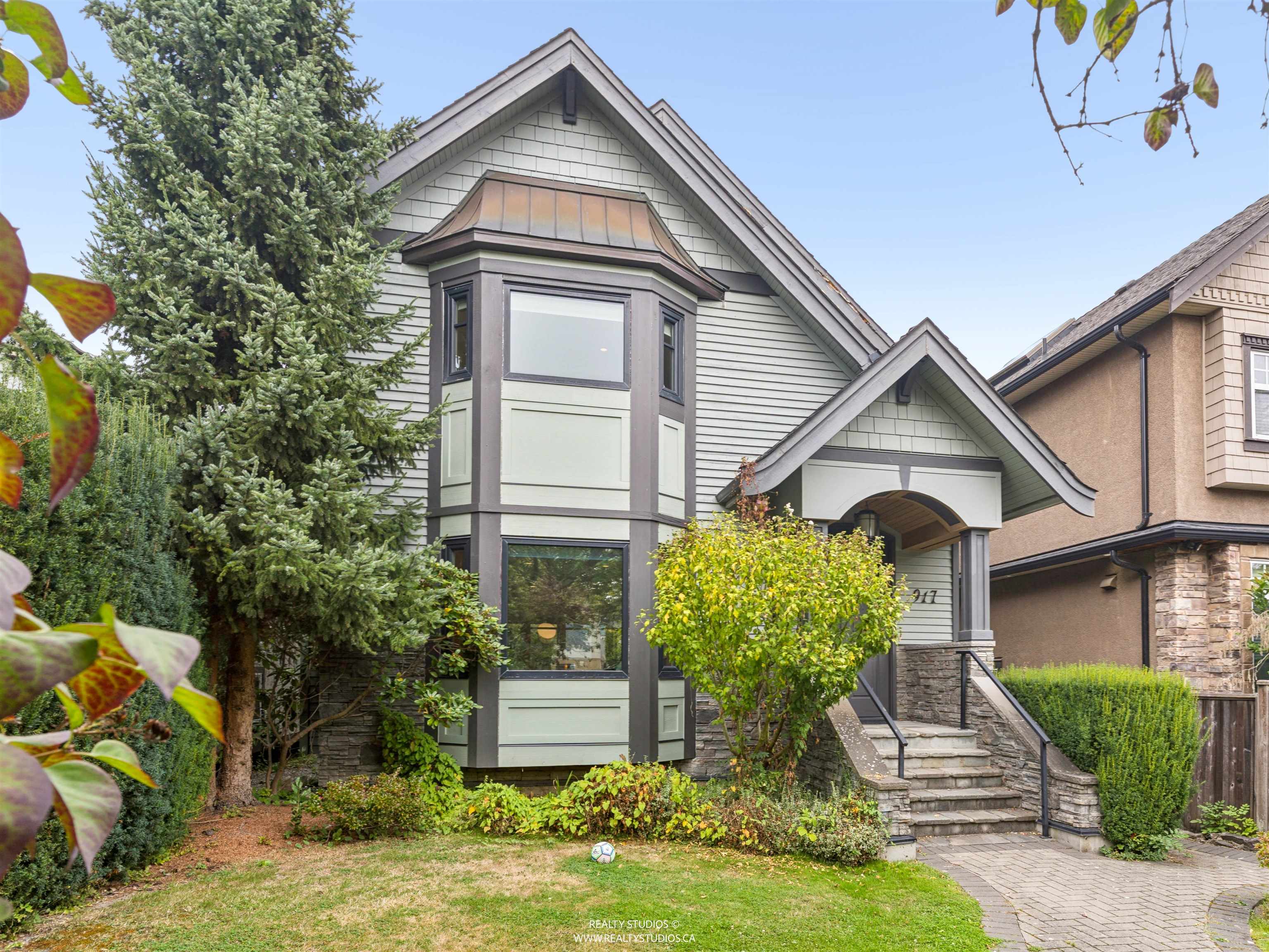 Gray gabled house with a projecting bay window, stone entry steps, and landscaped front yard.