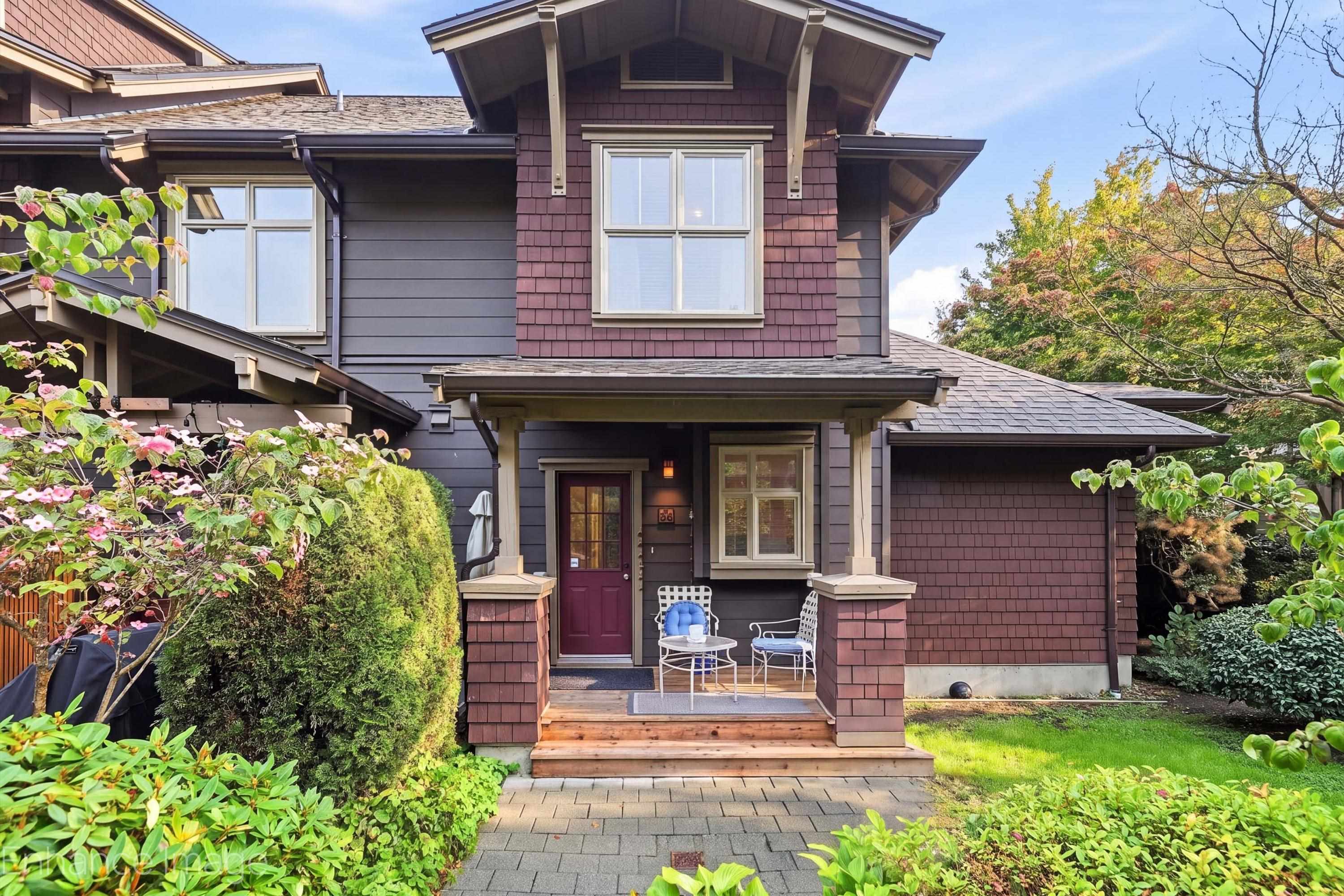 Two-story home with burgundy shingle accents, a covered porch, and landscaped front garden.