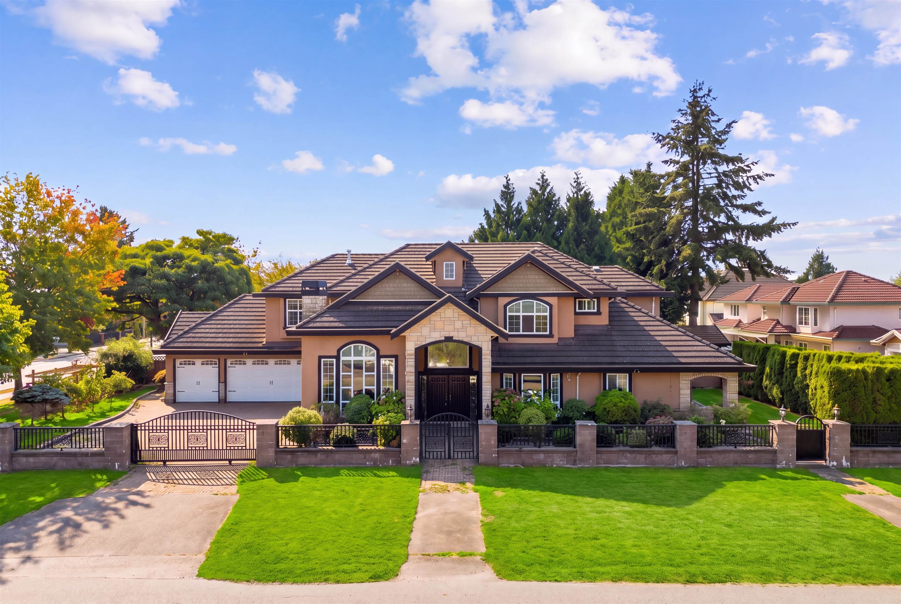 Large two-story house with stone entry, double garage, decorative metal gates, and landscaped lawn.
