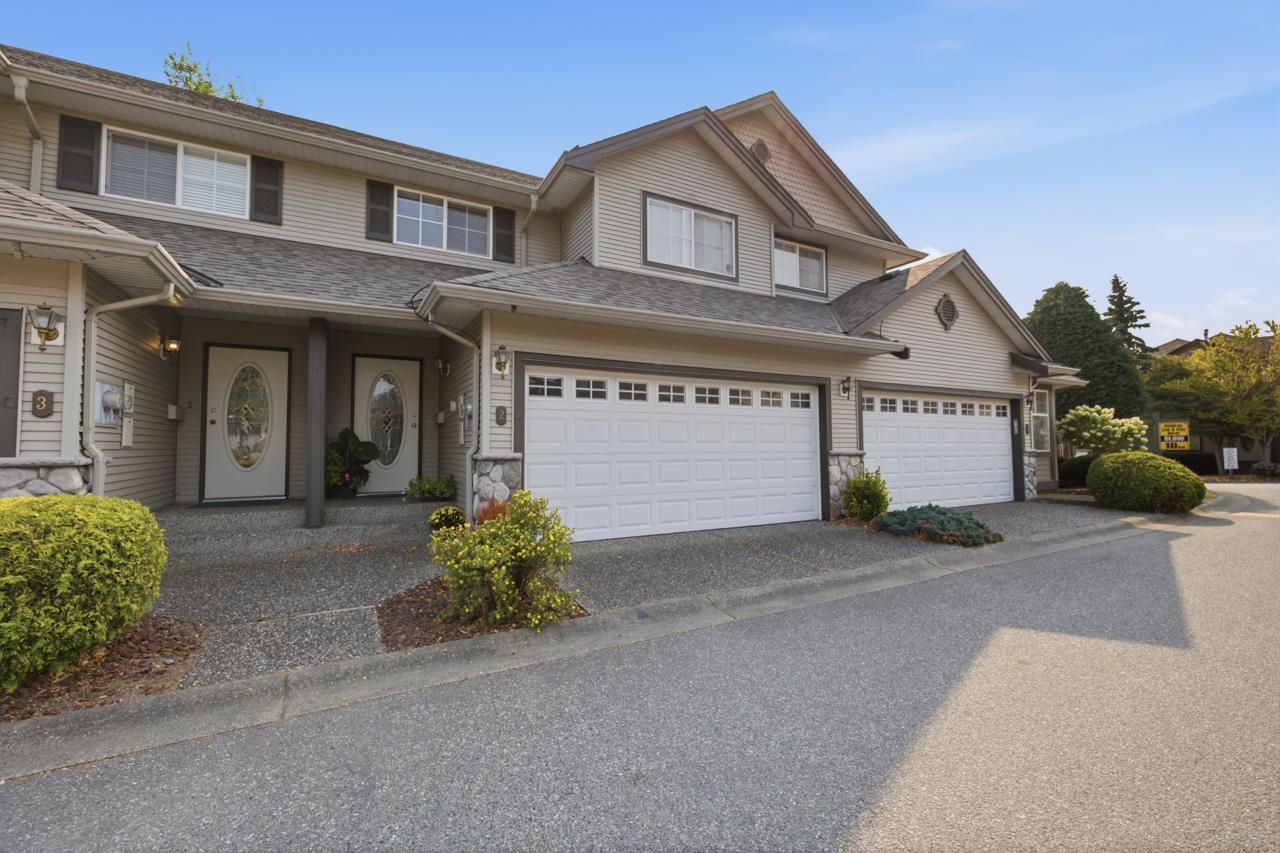Attached two-story homes with white garage doors, covered entrances, and landscaped shrubs.