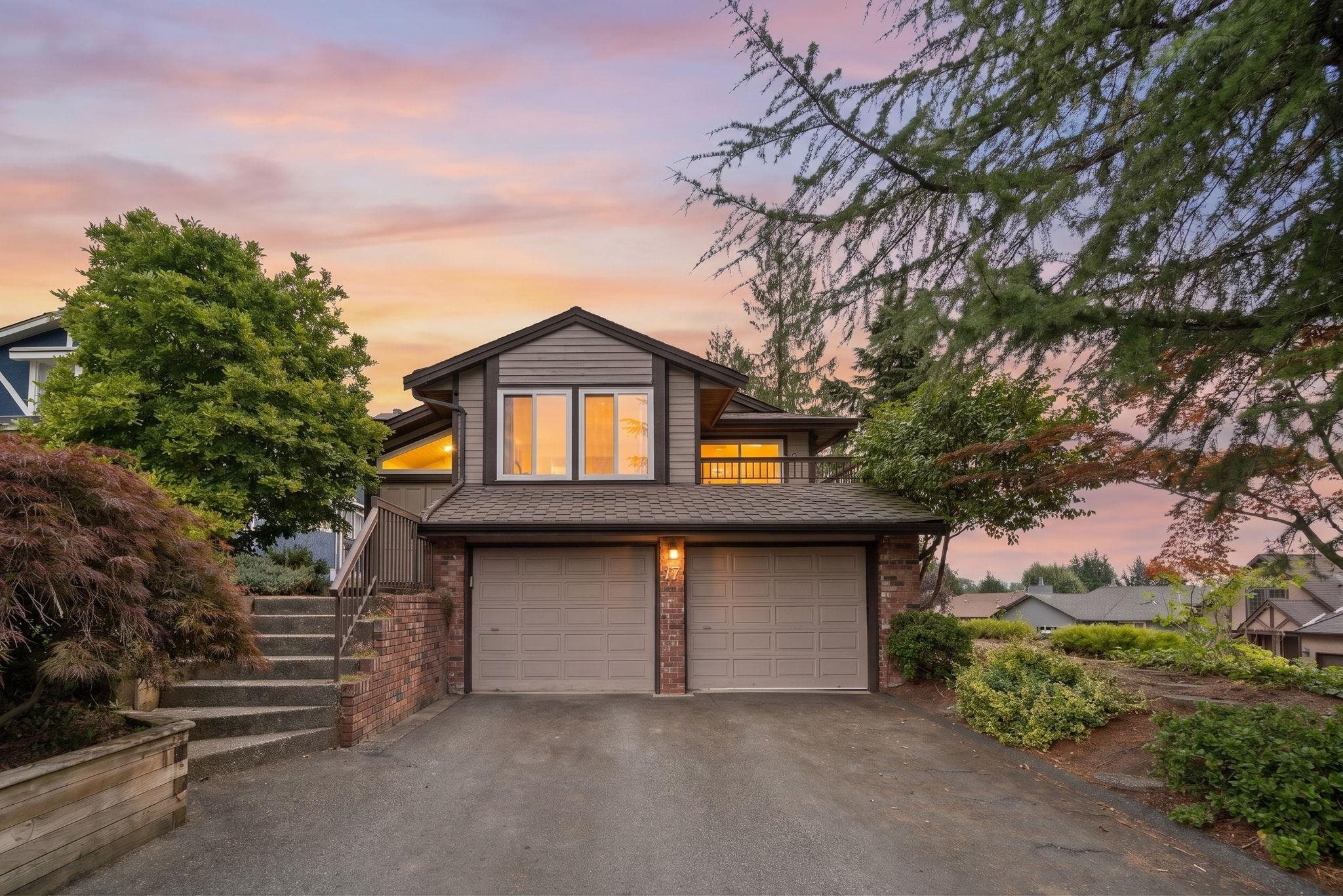 Two-story house with a double garage and landscaped yard at dusk.
