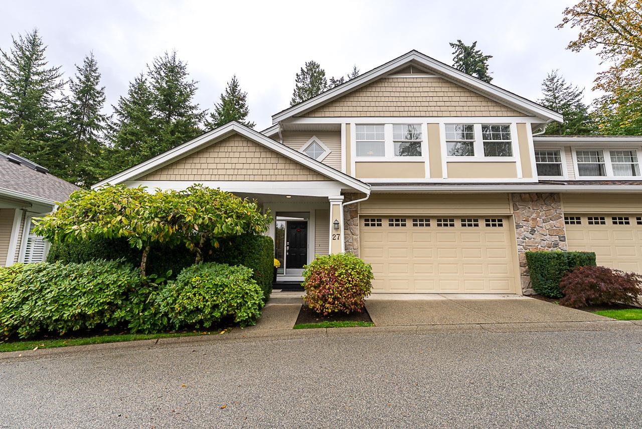 Two-story beige house with a double garage, stone accents, and landscaped front entry.