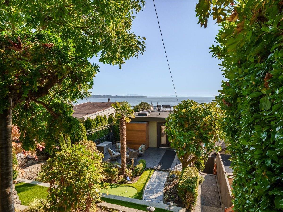 Landscaped backyard with a putting green, patio, and a view of the water.