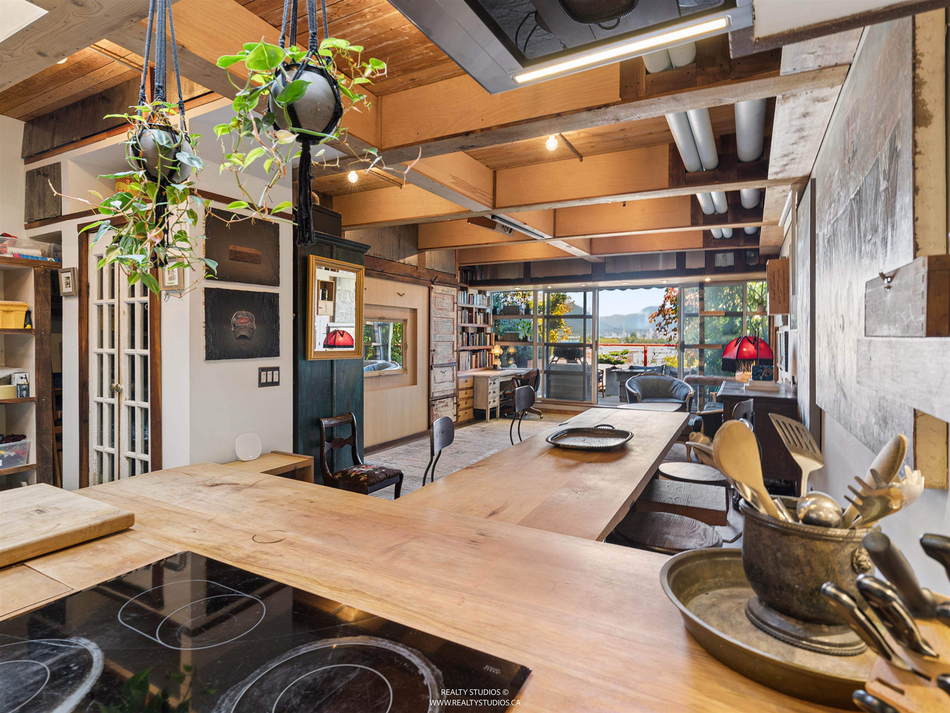 Open-plan kitchen and dining area with a long wood island, exposed beams, and mountain views.