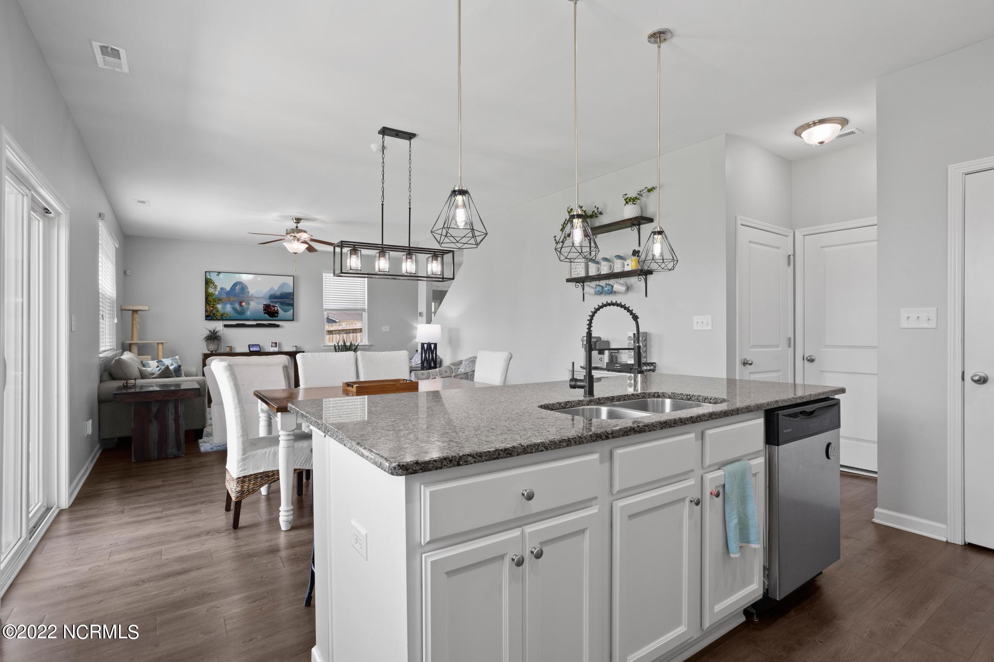Kitchen with a granite island and pendant lights, opening to a dining area and living room.