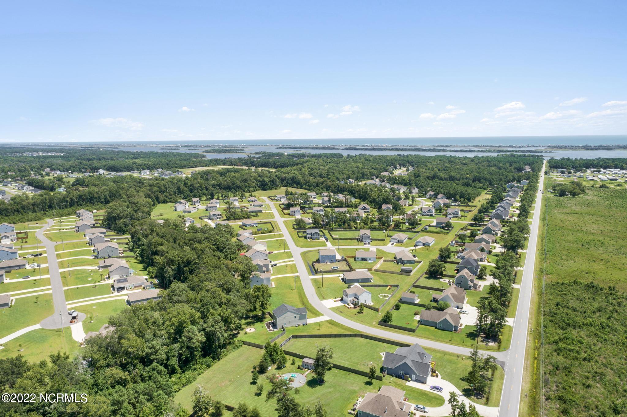 Aerial view of homes and wooded areas, with a waterway and ocean in the distance.