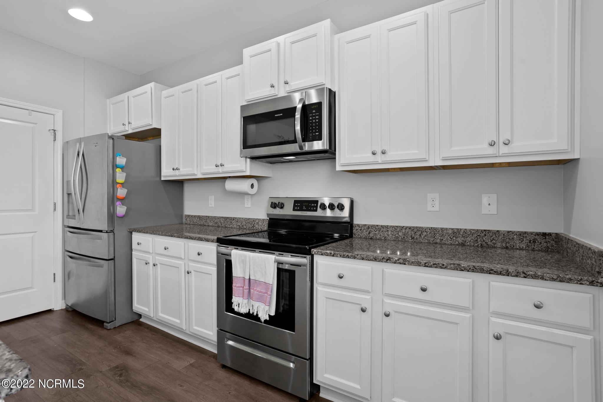 Kitchen with white cabinets, granite countertops, and stainless steel appliances.