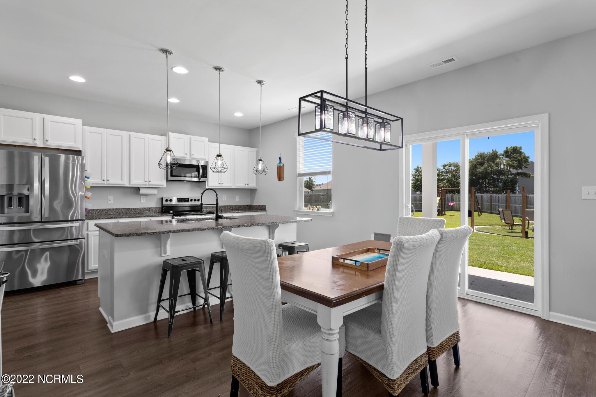 Open-plan kitchen and dining area with a granite island and sliding doors to the backyard.