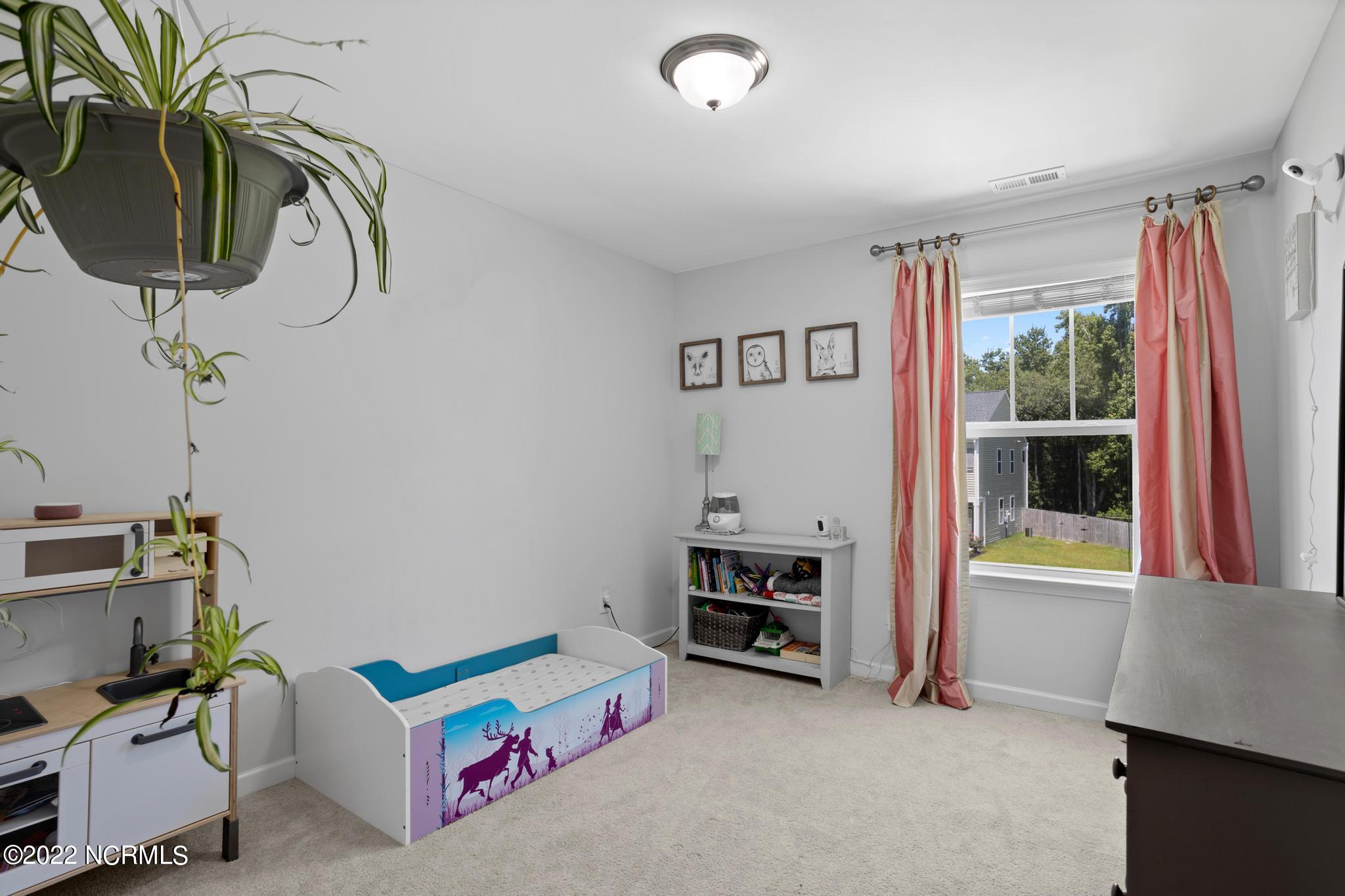 Furnished bedroom with an illustrated low bed, pink curtains, and a large window.