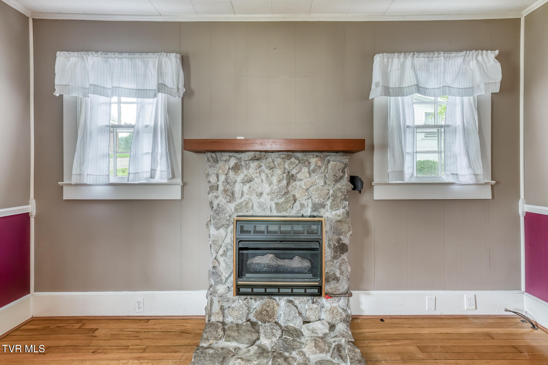 Living room with a floor-to-ceiling stone fireplace, gas insert, and hardwood floors.