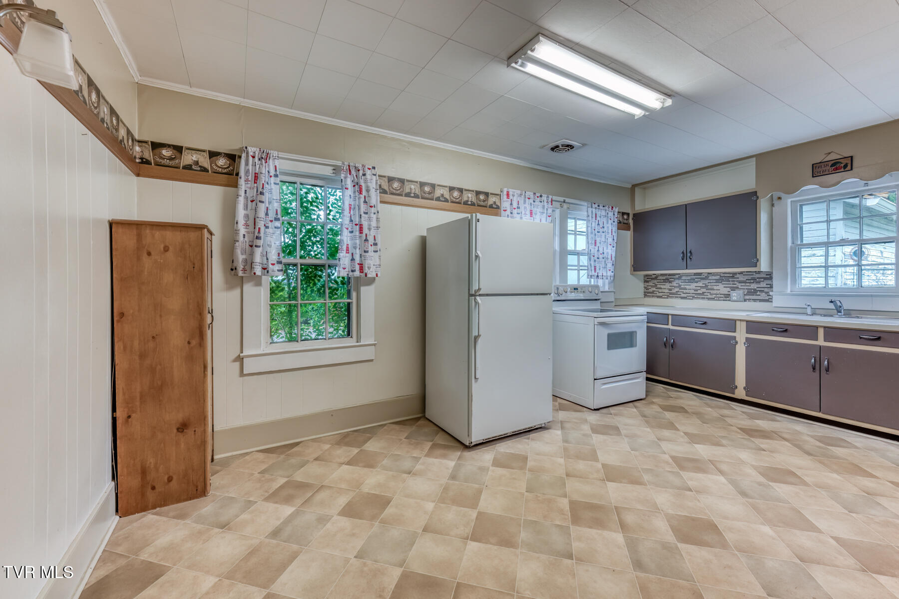 Kitchen with a white refrigerator and range, gray cabinets, and patterned tile flooring.