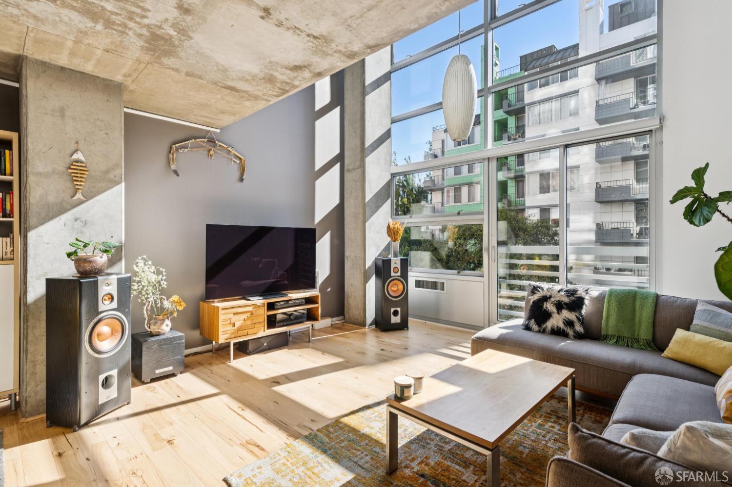 Contemporary living room with floor-to-ceiling windows, concrete details, and a gray sectional sofa.