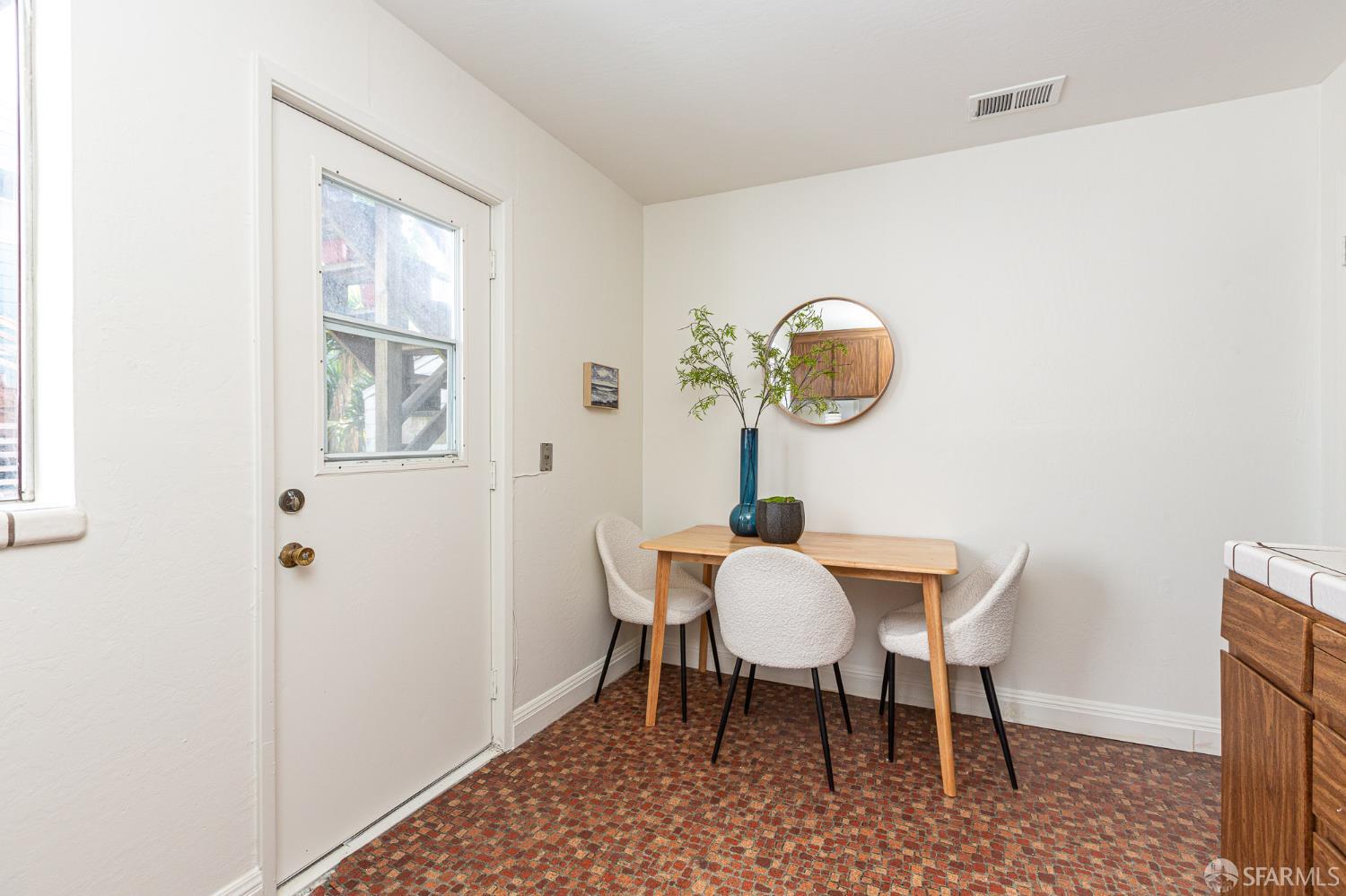 Dining nook with a small wood table, three upholstered chairs, and patterned tile flooring.