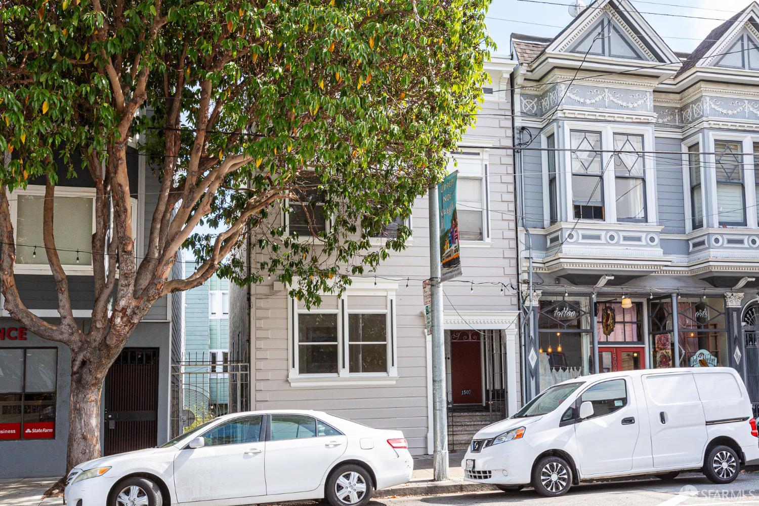 Church Street property beside an ornate gray-blue Victorian, partly screened by a large leafy tree.