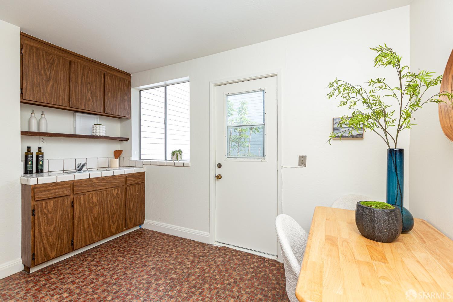 Kitchen and dining area with dark wood cabinets, patterned tile floor, and a wooden table with a potted plant.