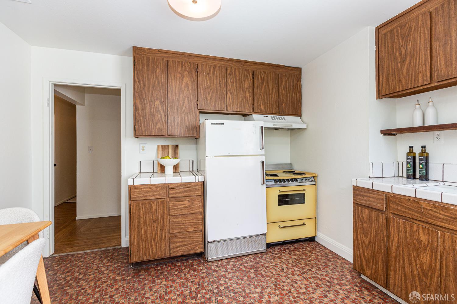 Kitchen with dark wood cabinets, a yellow range, and a colorful mosaic floor.