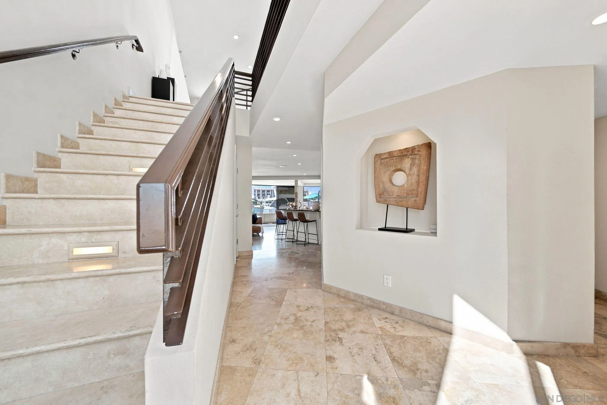 Entry hall with a stone staircase, dark wood railing, and sculptural artwork in a wall niche.