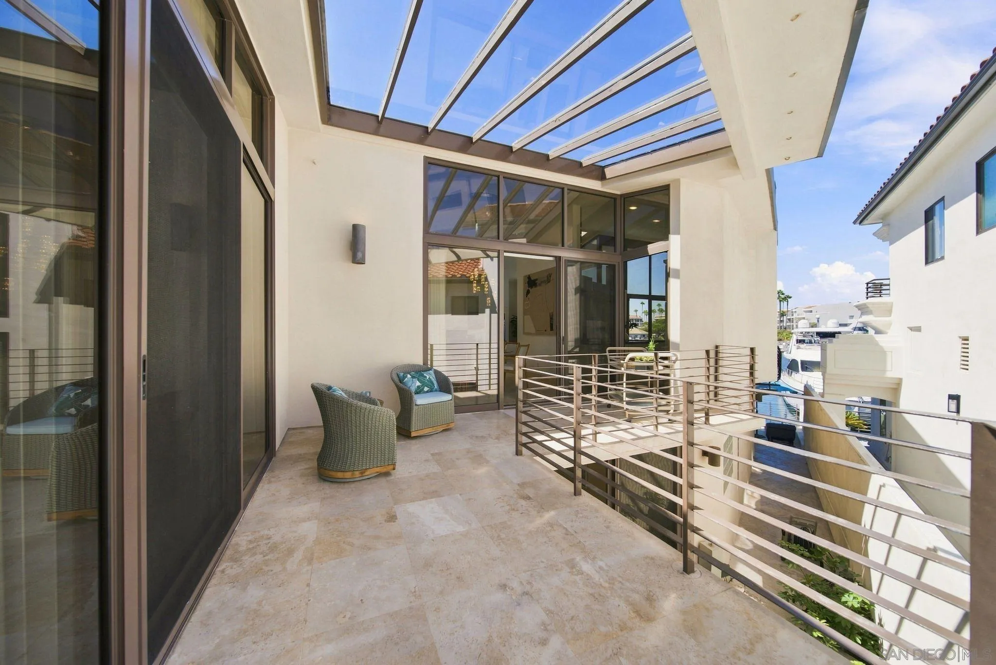 Covered terrace with a glass roof, wicker chairs, and a marina view.