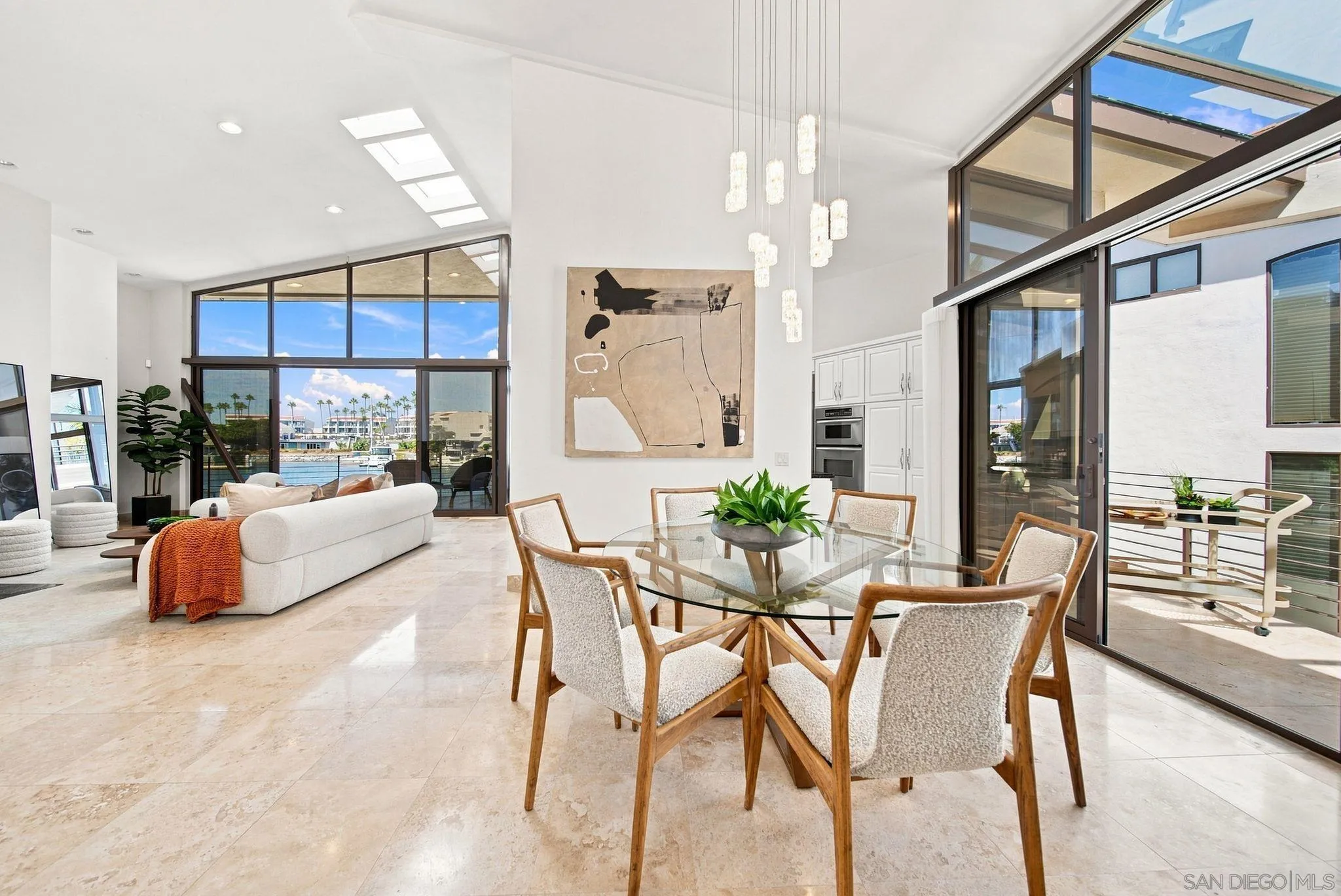 Open-plan living and dining room with marina views through tall windows and balcony doors.