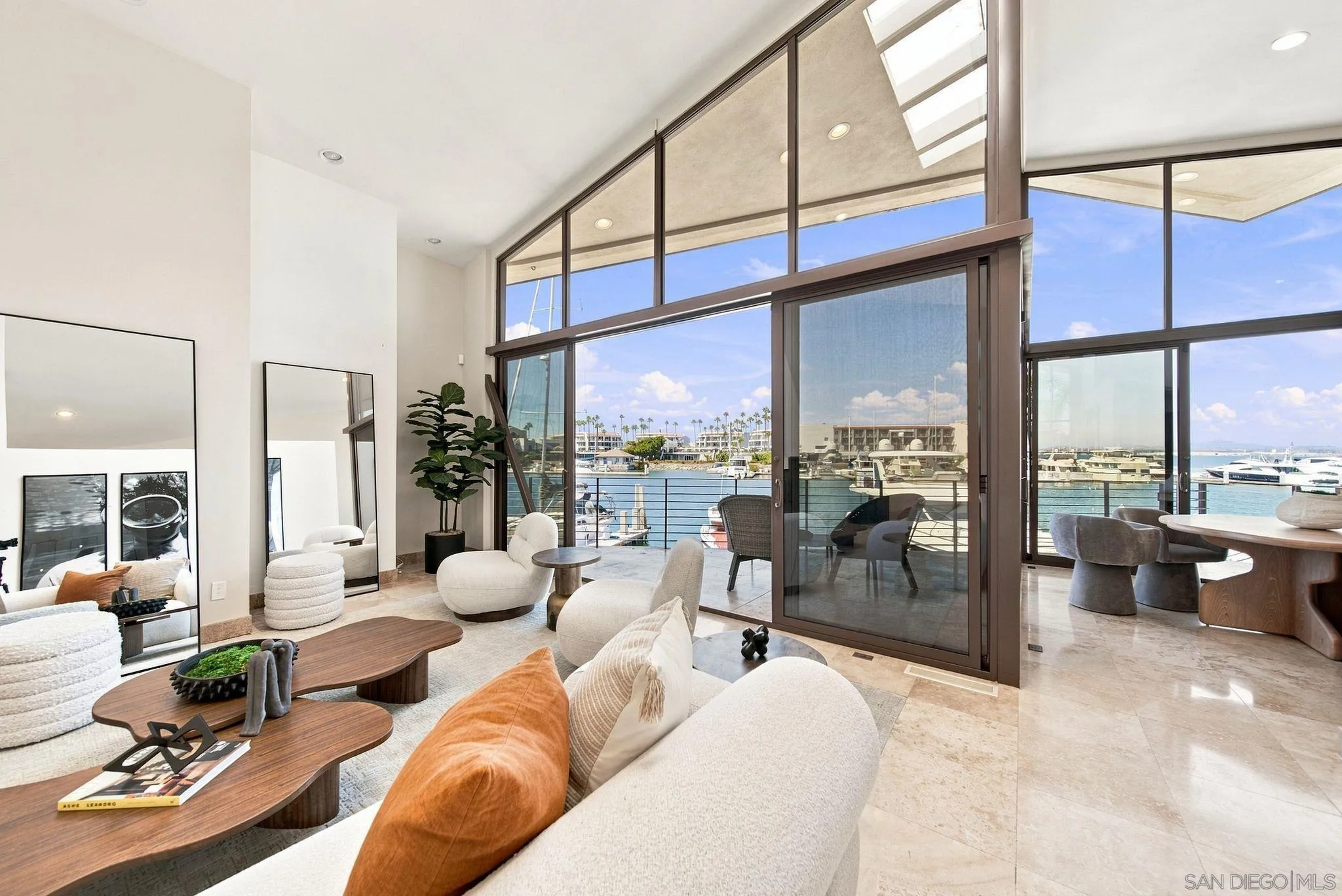 Furnished living room with dramatic floor-to-ceiling windows overlooking a marina.