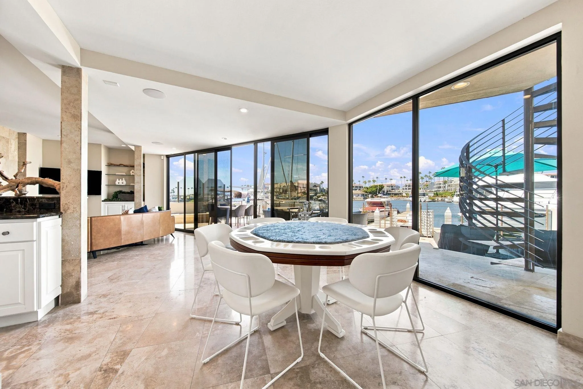 Dining area with a round table, floor-to-ceiling windows, and marina views.