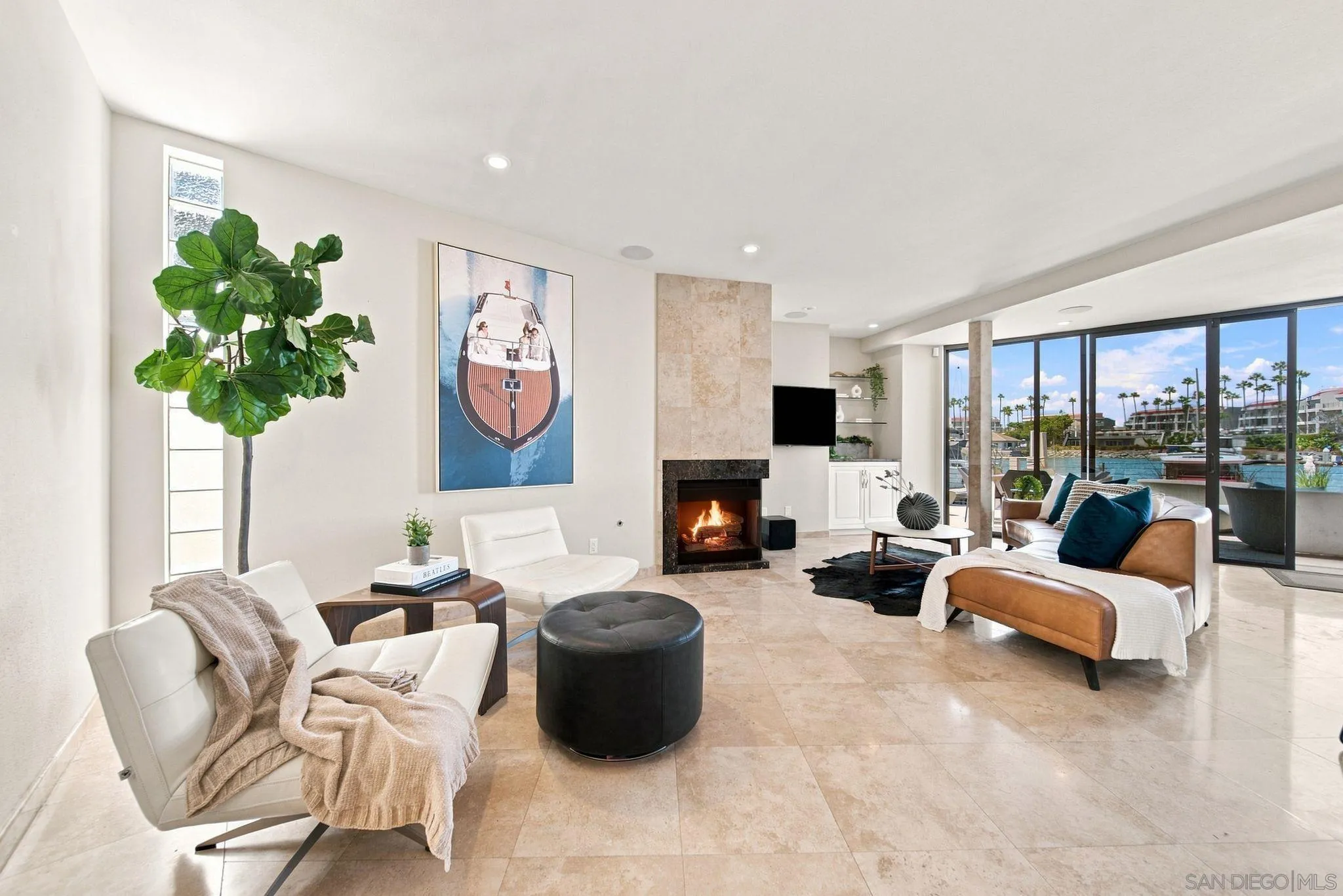 Living room with a fireplace and marina views through floor-to-ceiling windows.