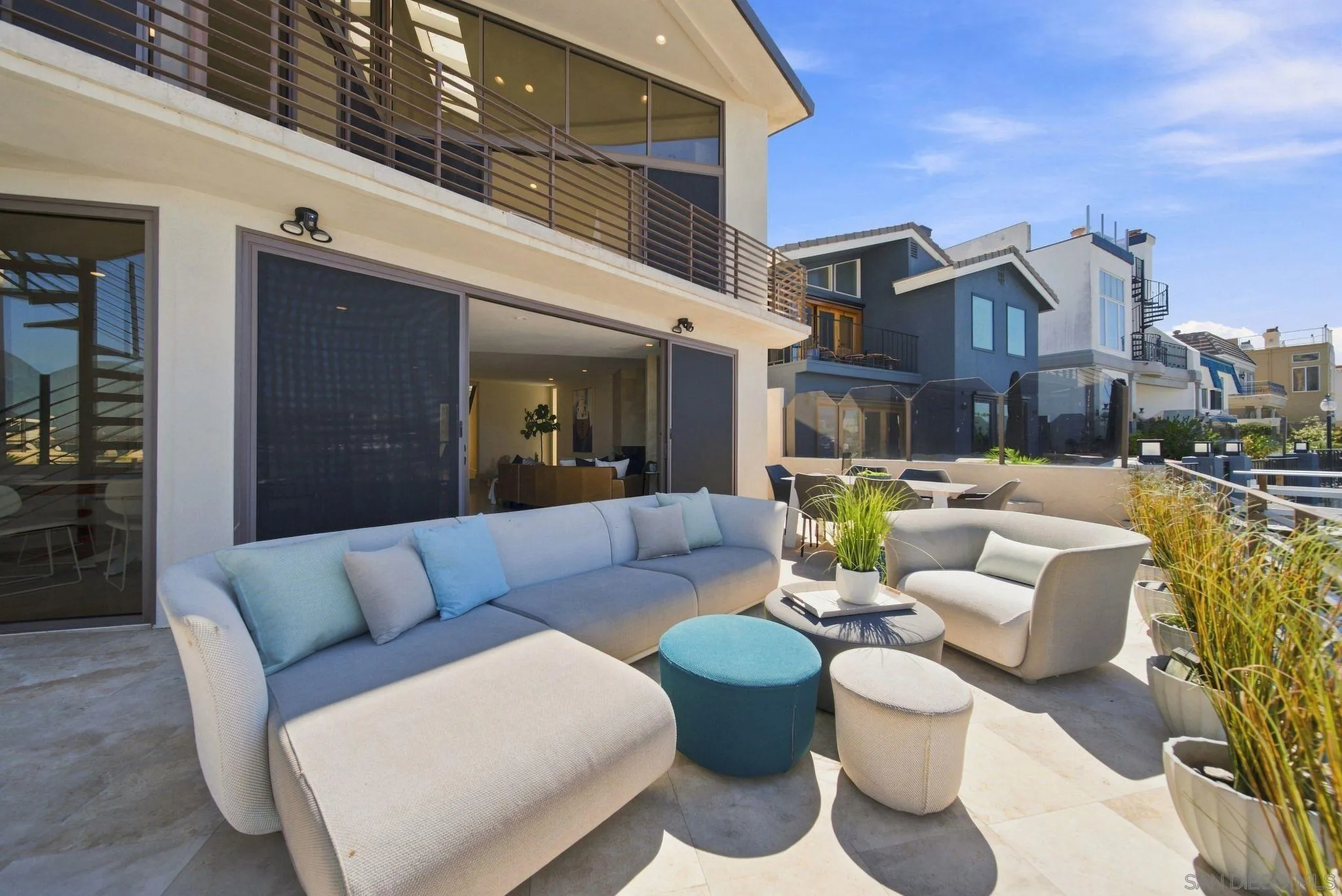 Modern home patio with a large sectional, lounge chairs, and potted grasses.