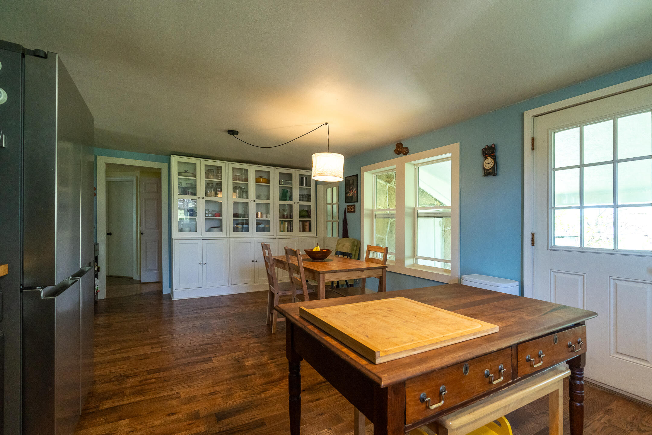 Kitchen and dining area with white glass-front cabinets and a large antique wooden worktable.