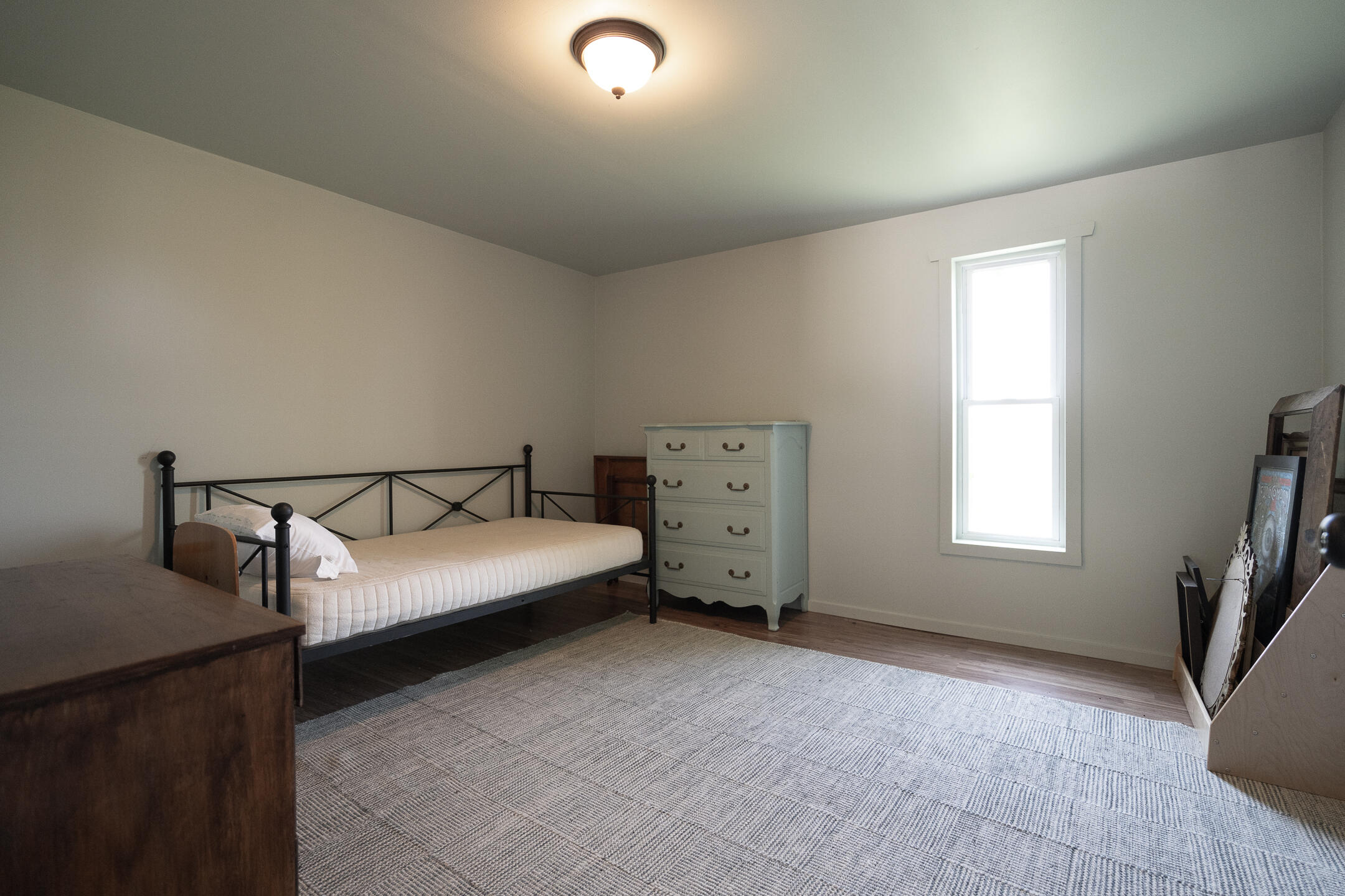 Bedroom with a metal-frame bed, pale blue dresser, and large gray patterned rug.