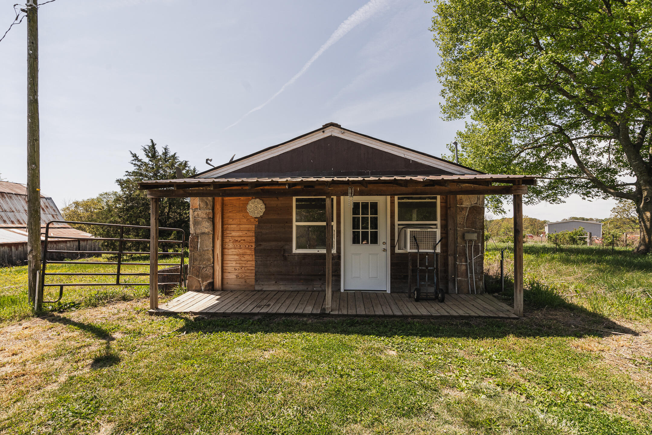Rustic wood-sided home with stone accents and a covered porch in a grassy yard.