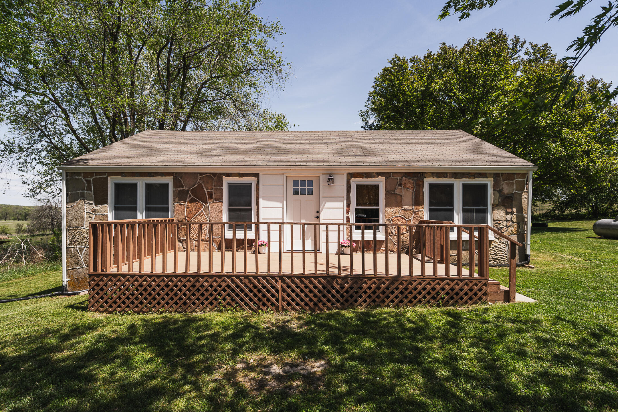 Single-story stone-front home with a raised wooden deck and lattice skirting.