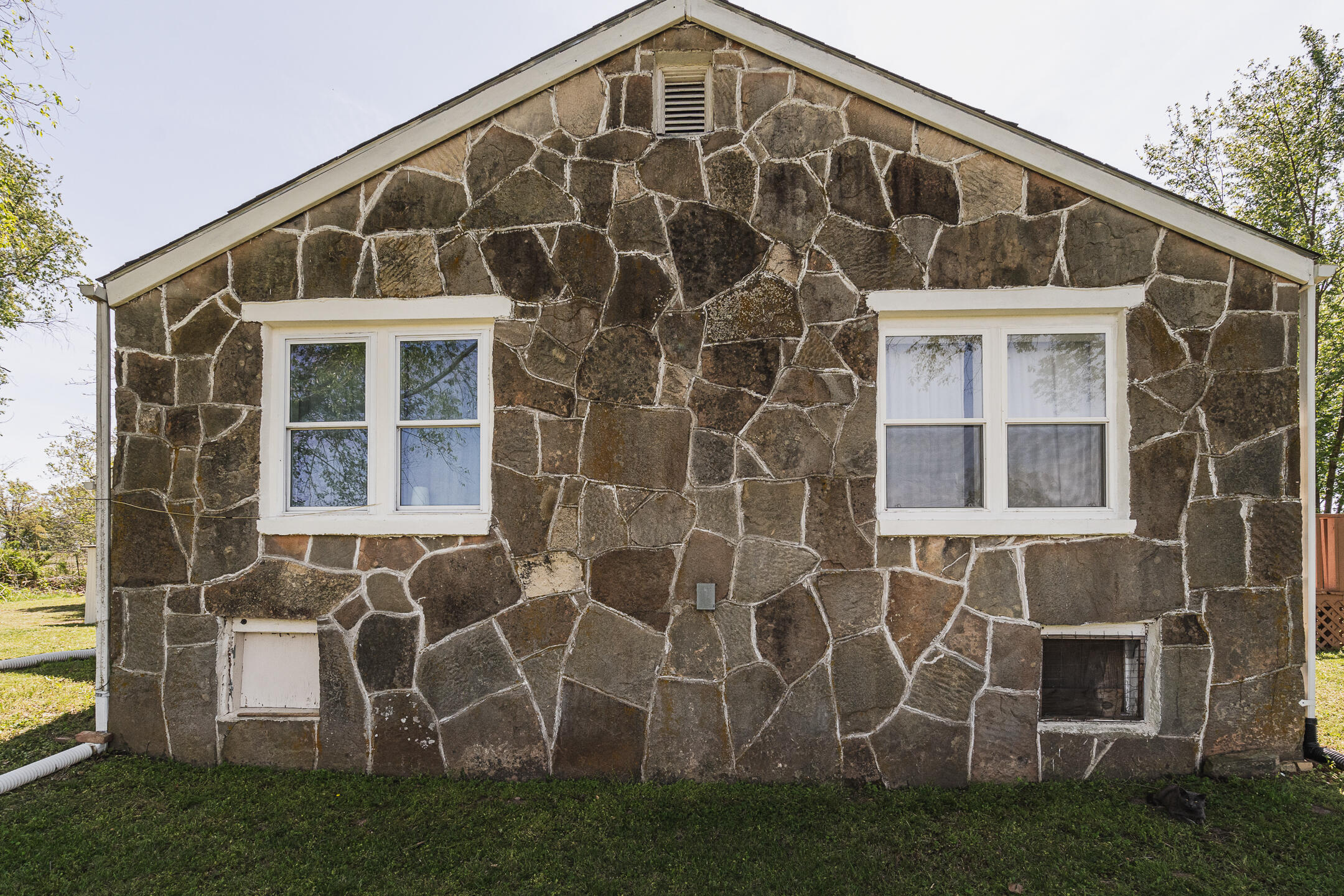 Stone house exterior with irregular stonework and white-trimmed windows.