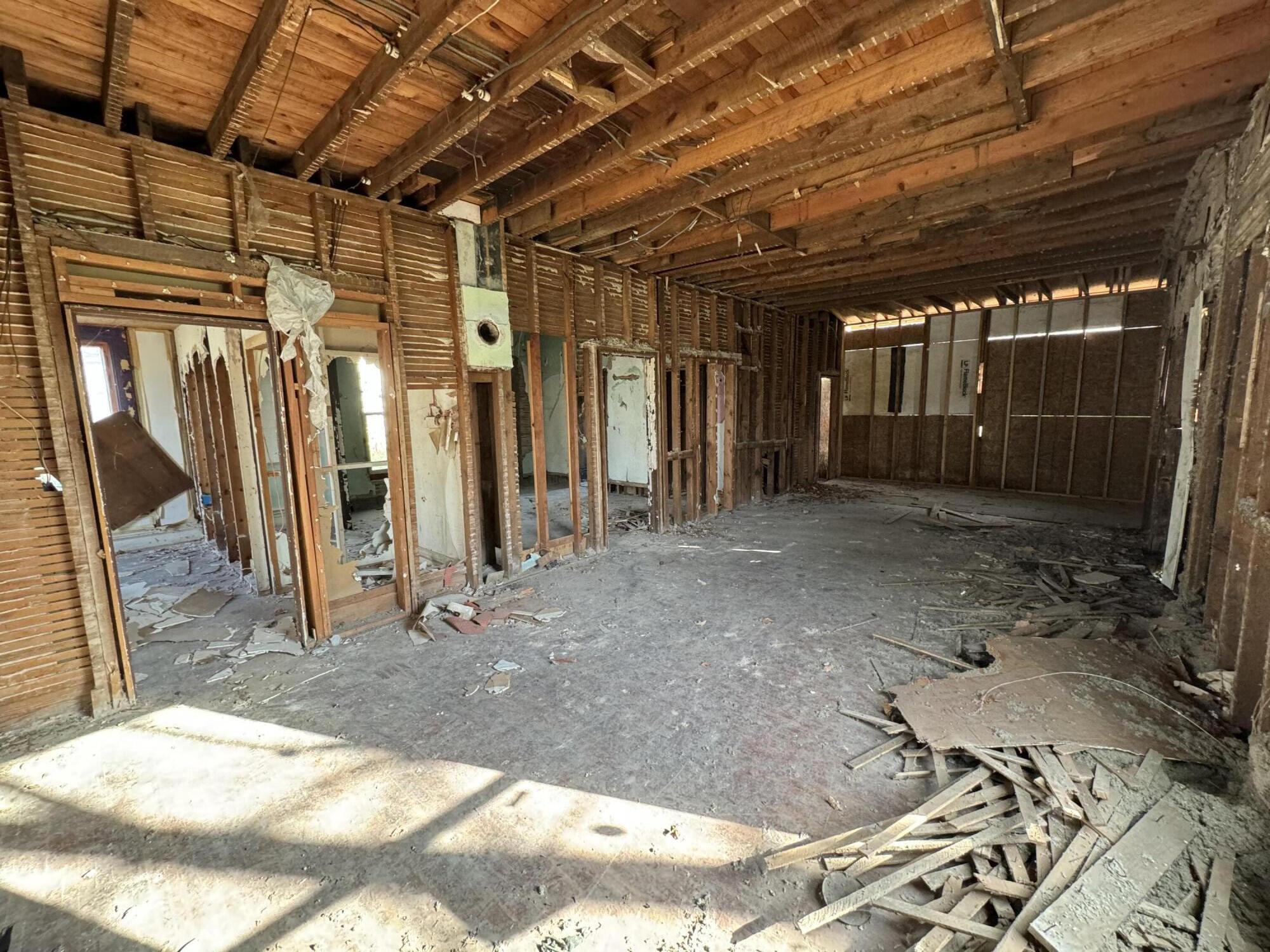 Gutted interior with exposed framing, ceiling joists, and demolition debris.